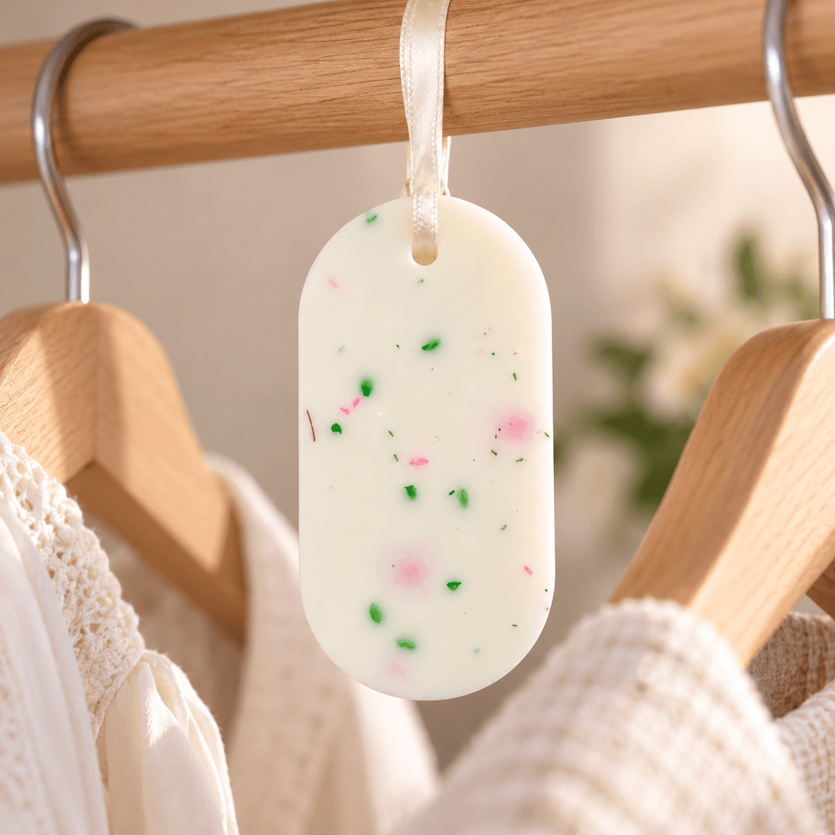 Odorizant pentru dulap din ceară naturală, cu parfum floral-fructat, agățat de bara de umerașe din dulap.